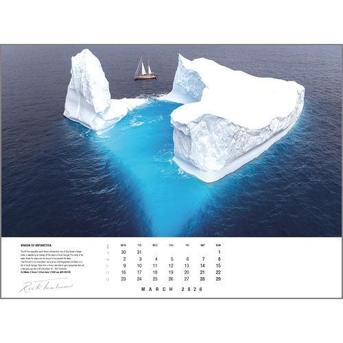 A sailboat sails by a huge iceberg with vivid blue underwater hues. The Rick Tomlinson Photography Rick Tomlinson Portfolio Calendar 2026 showcases this stunning March scene with icy whites and deep blue ocean.