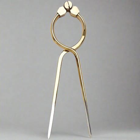 The Weems & Plath 8" One Hand Brass Divider stands upright against a plain gray background. This tool, designed by Weems & Plath, features a ring at the top for easy adjustments and pointed legs for precise distance measurements on maps or drawings, making it ideal for maritime navigation.