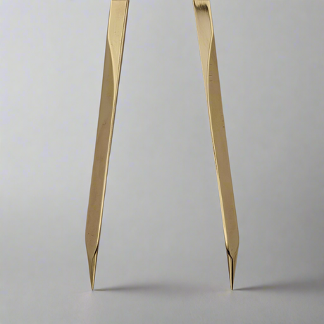 Close-up view of the Chartwright 7" Straight Brass Dividers, a precision instrument by Chartwright with its tips inserted into a white surface. The legs of the dividers are slightly angled, showcasing the precision points used for chart work and drawing circles. The background is plain and softly blurred.