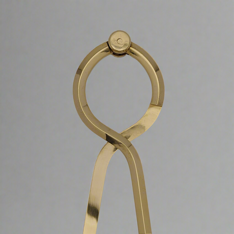 A close-up view of the Chartwright 8" Single-Handed Brass Dividers reveals a precision instrument with a distinctive loop at the top. The legs of these dividers are crossed near the top, creating a stylish and sleek design against a plain gray background—an ideal tool for chartwork.