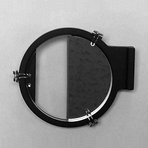 A SailorShop black circular wall mirror with a hinge attachment echoes the precision of the Celestaire Astra IIIB Deluxe Sextant, half reflecting a textured surface. Much like celestial navigation, it forms two distinct sections: one illuminated and the other in shadow, expertly directing your gaze across its face.
