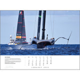 The Rick Tomlinson Portfolio Calendar 2025 by Rick Tomlinson Photography features a sleek sailboat with foils gracefully gliding over blue water on the January 2025 page, with a second boat visible in the background. This breathtaking sailing photograph includes dates and vessel details, with sails prominently displaying branding and logos.