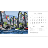 The image, taken by renowned photographer Rick Tomlinson, showcases a lively sailing race with vividly colored sailboats adorned with flags and numbers on the water. It's featured in the July 2025 edition of the Rick Tomlinson Desk Calendar by Rick Tomlinson Photography, highlighting the Waszp World Championships in Norway.