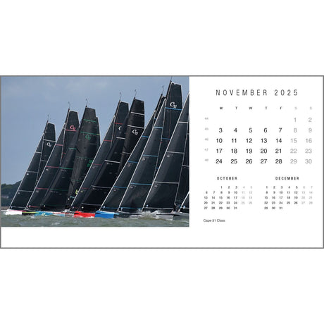 In a breathtaking photograph by Rick Tomlinson Photography, a fleet of sleek black sailboats races beneath a cloudy sky. To the right, the Rick Tomlinson Desk Calendar 2025 displays November, with hints of October and December visible. The elegant inscription "Cape 31 Class" is featured below.