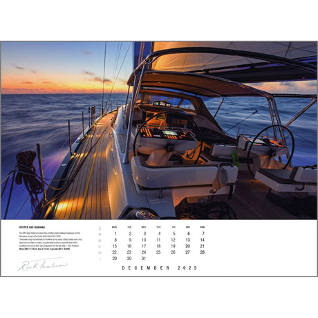 A sleek yacht glides on the ocean at sunset, warm sunlight illuminating its deck and controls. The sky is a mix of orange and blue hues. This captivating scene adorns the December 2025 page of the Rick Tomlinson Portfolio Calendar 2025 by Rick Tomlinson Photography, featuring exquisite sailing photography.