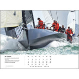 Sailors in red gear race a sleek boat through green waves in February’s feature of the Rick Tomlinson Portfolio Calendar 2026 by Rick Tomlinson Photography.