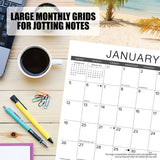 On a desk with a Willow Creek Press coffee mug, laptop, pens, and paperclips, the Willow Creek Tall Ships 2025 Calendar is opened to January showcasing large grids for notes with a palm tree and beach scene in the background.