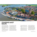 Aerial view of a Dutch harbor town on the Standing Mast Route, with boats, classic houses, and green fields—a perfect cover for the Adlard Coles Shore Guide: The Netherlands by Adlard Coles.