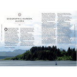 An image from "Under Wide and Starry Skies" by Adlard Coles showcases a yacht journey through Geographic Harbor, Alaska, with text on exploring the scenic mountains and harbor. The headline reads "Geographic Harbor, Alaska, USA.