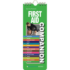 The "First Aid Companion" by Fernhurst Books is a green spiral-bound guide with an image of first aid in action, covering resuscitation, bleeding, burns, and more—ideal as an emergency maritime first aid reference.