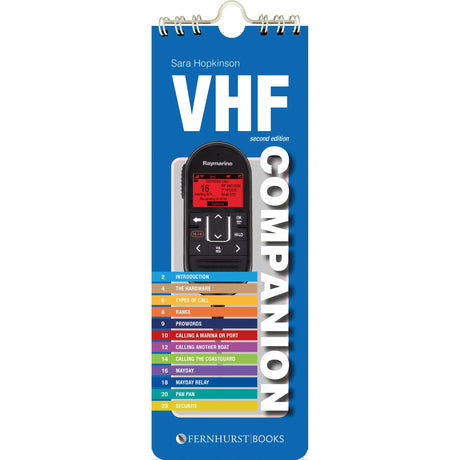 The "VHF Companion" by Fernhurst Books is a spiral-bound guidebook with a VHF radio cover and colorful numbered contents, serving as an essential reference for radio call and DSC procedures.