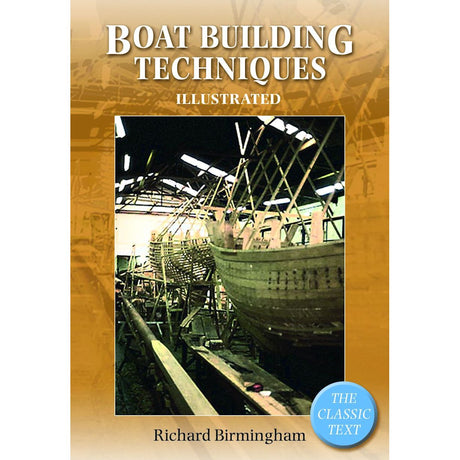 The cover of "Boatbuilding Techniques Illustrated" by Adlard Coles features a large wooden boat under construction in a workshop. Scaffolding and framing emphasize the boatbuilding skills involved, while a warm yellow backdrop is accented by a blue label that reads "The Classic Text.