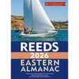 A white sailboat with people sails on blue water near green hills. The cover reads: "Reeds Eastern Almanac 2026" by Reeds, featuring North Sea navigation advice and tide tables for covered regions.