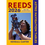 A person holds a sextant under a clear blue sky. The book, "Reeds Astro Navigation Tables 2026" by Reeds, features essential sight reduction almanac data with a yellow and purple cover design.