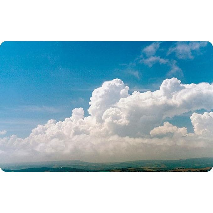 Large, puffy white clouds from The Cloud Deck by David & Charles drift against a bright blue sky above a distant, rolling landscape.