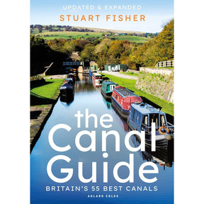 The cover of "The Canal Guide" by Stuart Fisher, published by Adlard Coles, features vibrant narrowboats sailing a sunlit canal surrounded by lush greenery. It highlights "Updated & Expanded" and "Britain’s 55 Best Canals," making it an essential guide to Britain's waterways heritage.