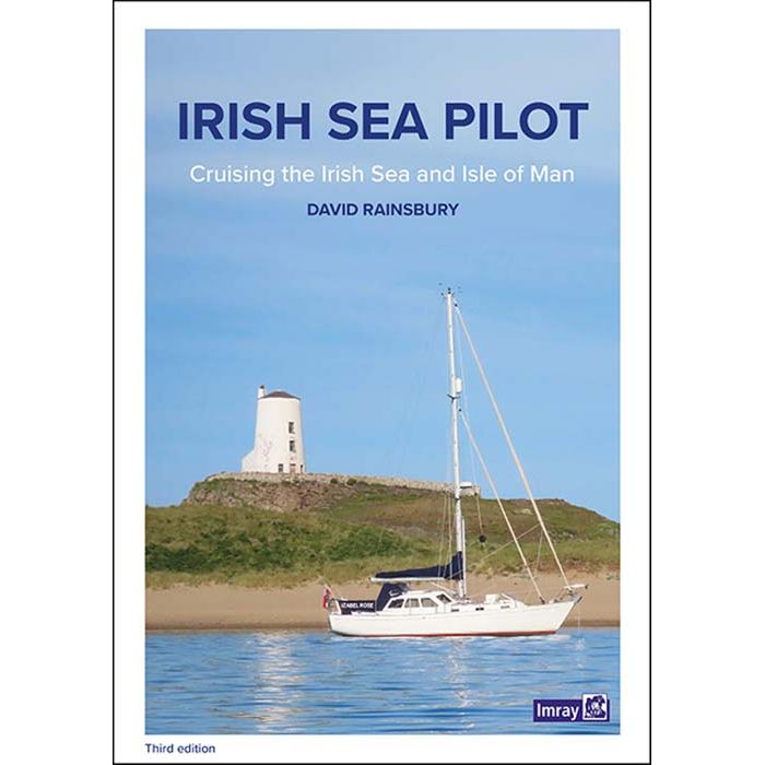 Cover of the book "Irish Sea Pilot" by David Rainsbury, published by Imray. The third edition is a comprehensive cruising guide featuring a sailboat anchored near a sandy shore with a white lighthouse on a grassy hill under a clear blue sky. The subtitle reads, "Cruising the Irish Sea and Isle of Man.