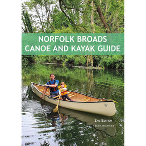 A man and a child paddle a canoe along a peaceful, tree-lined river in the picturesque Norfolk Broads. The book cover displays "Norfolk Broads Canoe and Kayak Guide" by Steve Maloney, published by Pesda Press, providing expert guidance on the top paddling routes across this scenic area.
