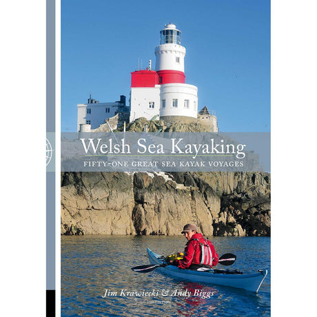 A kayaker paddles along a rocky shoreline beneath a white and red lighthouse under a clear blue sky. Text reads: "Welsh Sea Kayaking" by Pesda Press—your essential guide to 51 great sea kayak voyages for exploring the stunning Welsh coastline.