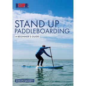 A person paddles on a blue inflatable paddle board in calm water beneath a clear sky. The book, "Stand Up Paddleboarding: A Beginner's Guide" by Fernhurst Books, is shown.