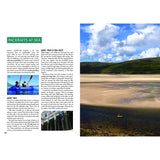 A magazine spread features "Packrafting: A Beginner's Guide" by Fernhurst Books, with tips and photos—one showing two people kayaking, the other a yellow packraft on a sandy shore beneath a blue sky with scattered clouds.