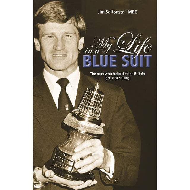 A man in a suit holds a large sailing trophy. The book cover reads: "My Life In A Blue Suit" by Fernhurst Books, telling the story of Olympic sailing coach Jim Saltonstall MBE, who helped make Britain great at sailing.