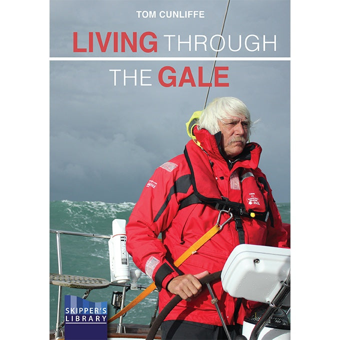 A man in a red jacket stands at the helm of a sailboat in rough seas, with "Living Through The Gale" by Fernhurst Books displayed above him, capturing the spirit of heavy weather sailing.