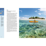 A person paddles a yellow kayak in Fiji’s clear waters by palm-lined beaches and blue skies. On the left, text about sea kayaking and the Fiji experience from "Ultimate Paddling Adventures" by Fernhurst Books is displayed.