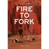 The cover of the Aussie cookbook "Fire to Fork," published by Exploring Eden Media, illustrates someone cooking over a campfire amid striking red desert cliffs, accompanied by a black and white dog that embodies the spirit of adventure cooking in the great outdoors.