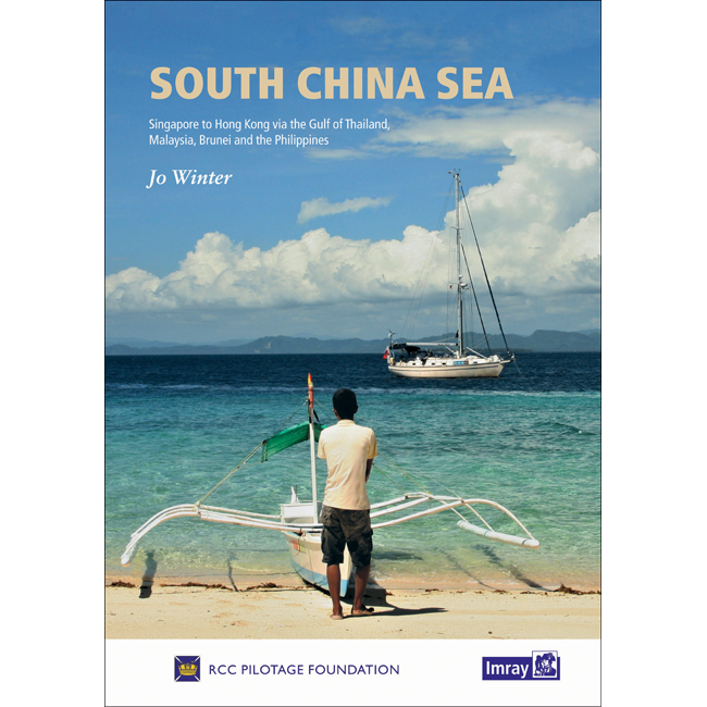 Book cover of "South China Sea" by Jo Winter, published by Imray. The illustration shows a person standing on a Southeast Asian beach, looking out at the sea with a traditional outrigger canoe in front and a yacht anchored nearby. The partly cloudy sky and the horizon-stretching sea evoke an inviting cruising guide ambiance.