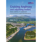 Aerial view of a coastal town with a river winding through green hills under blue sky. Book cover: "Cruising Anglesey and Adjoining Waters" by Imray—an essential North Wales coast guide for pilots. Imray logo top right.