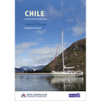A white sailboat with red accents glides on tranquil waters amid mountains and greenery, beneath a cloudy sky. The book cover displays "Chile" by Imray, a leading sailing guide to the region.