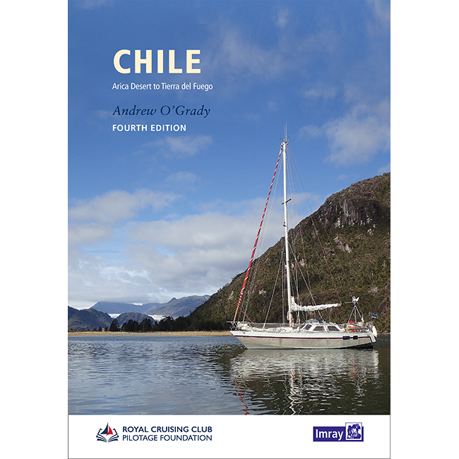 A white sailboat with red accents glides on tranquil waters amid mountains and greenery, beneath a cloudy sky. The book cover displays "Chile" by Imray, a leading sailing guide to the region.