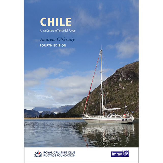 A white sailboat with red accents glides on tranquil waters amid mountains and greenery, beneath a cloudy sky. The book cover displays "Chile" by Imray, a leading sailing guide to the region.