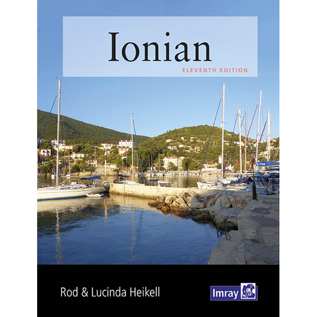 The cover of the Imray "Ionian" guide features sailboats in a tranquil harbor against green hills and houses. The bold title and authors Rod & Lucinda Heikell emphasize its reputation as a trusted resource for Greek cruising.