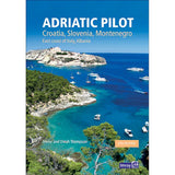 The cover of the "Adriatic Pilot" by Imray, authored by Trevor and Dinah Thompson, features a breathtaking coastal scene with turquoise waters, boats, and lush greenery beneath a clear blue sky. This indispensable cruising guide delves into the captivating Croatian coastline as well as regions of Slovenia, Montenegro, Italy, and Albania.