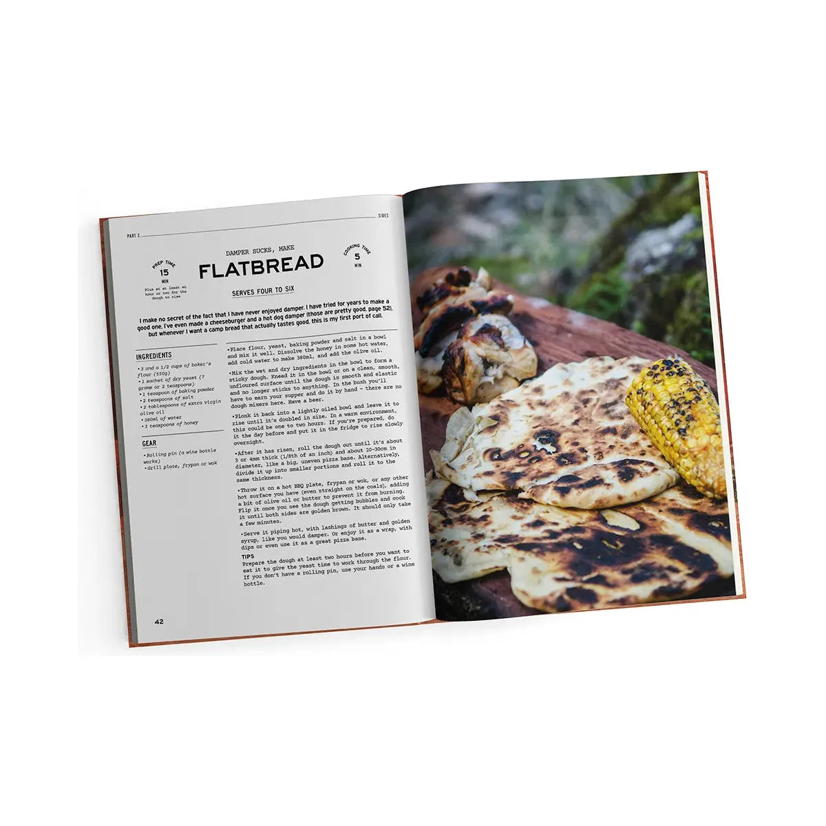 The "Fire to Fork" cookbook by Exploring Eden Media features an enticing flatbread recipe on the left page, paired with a vibrant photo on the right that showcases grilled flatbread with roasted garlic and corn. Perfect for campfire cooking, this recipe comes complete with lists of ingredients, step-by-step directions, and gear suggestions for an unforgettable outdoor cuisine adventure.