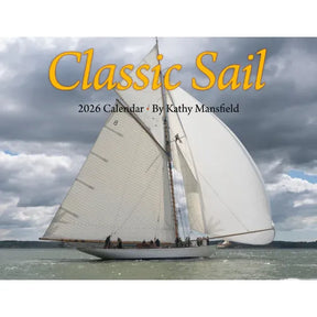 A white sailboat with tall sails drifts on calm water beneath clouds. Text: "Classic Sail 2026 Calendar · Kathy Mansfield." Ideal for classic sailboat enthusiasts and nautical photography fans.