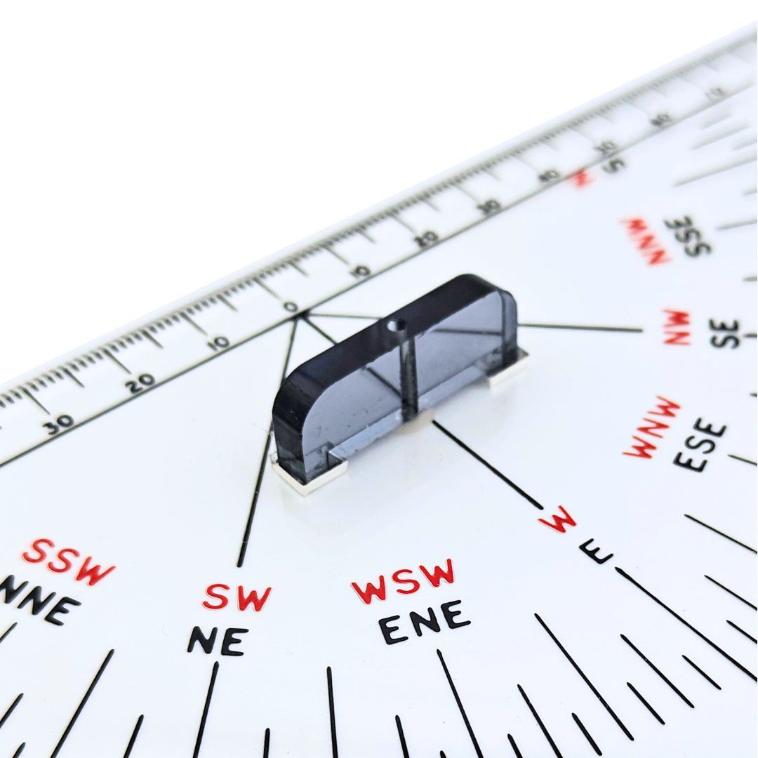 Close-up of a 12" Navigation Triangle by Charles, Smith & Reddish, featuring a transparent rotating compass rose that's perfect for nautical charts. It displays cardinal and intercardinal directions in black and red, with degree measurements along the triangle's edges.