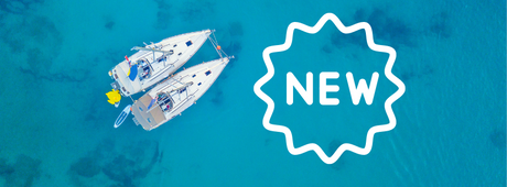 Two sailboats float on clear blue water viewed from above. A white starburst shape with the word "NEW" is overlaid on the right side of the image.