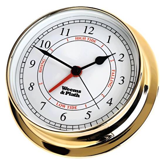 The Weems & Plath Brass Endurance 125 Time & Tide Clock, a nautical essential, features a brass case and white face that displays the times for high and low tides. It includes black numerals and red tide level indicators labeled "rising" and "falling," with the brand name Weems & Plath elegantly displayed on the face.