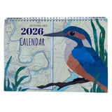 The Hannah Wisdom Coastal Calendar 2026 by Hannah Wisdom Textiles features a map-themed cover with an illustrated kingfisher among green reeds, inspired by textile art, and "To Gunnislake 2026 Calendar" at the top.