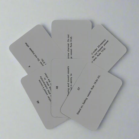 Image of six grey rectangular Flip Cards - Rule of the Road slightly spread out in a fan shape against a plain white background. Each card has printed text with various rules and guidelines related to mariner navigation and Col Regs, but the text isn't fully legible due to the angle and overlap of the cards.