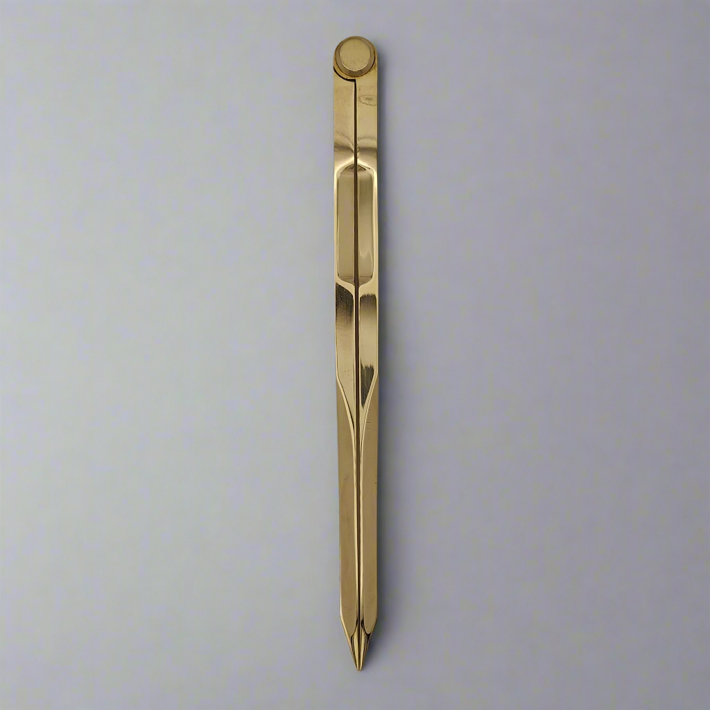 A sleek, gold-colored Chartwright 7" Straight Brass Divider lies horizontally on a light-colored surface. The divider, reminiscent of a precision instrument, boasts a modern, minimalist design with a smooth surface and pointed ends.