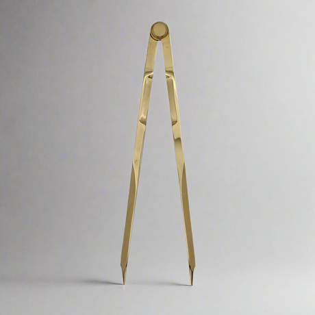 The Chartwright 7" Straight Brass Dividers, a precision instrument from the renowned brand Chartwright, stands upright against a plain, light gray background. The tool's sharp pointed ends and slightly parted legs form a narrow V shape, perfect for meticulous chart work.