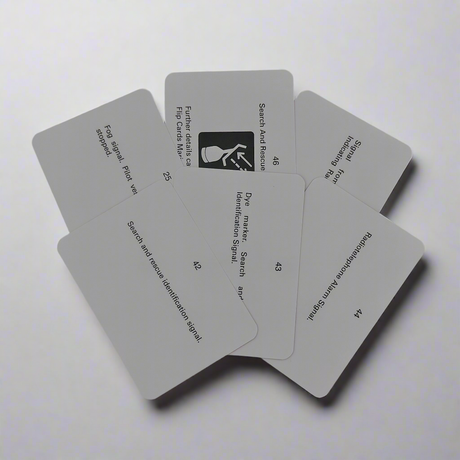 A splayed arrangement of six Flip Cards - Sound and Light Signals cards on a flat surface. Each card has black text with titles like "Search and Rescue Identification Signal" and numbered instructions. The top card features a pictogram of a hand holding a card with waves emitting from it, crucial for navigational regulations.