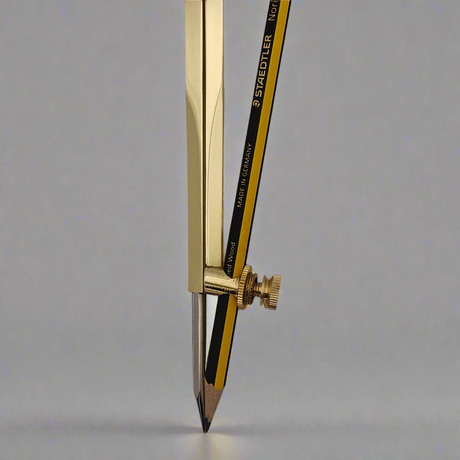 A close-up image of a Chartwright 8" Brass Pencil Compass, featuring a yellow and black pencil inserted into one of its arms. The compass is positioned upright on a gray surface. The text "STAEDTLER" and "Made in Germany" are visible on the pencil.