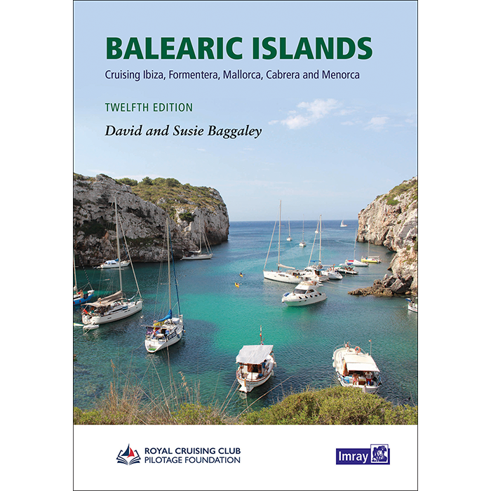 Cover of the book "Balearic Islands" by Imray, featuring a coastal scene with sailboats anchored in clear turquoise water, surrounded by rocky cliffs. The text reads "Cruising Ibiza, Formentera, Mallorca, Cabrera, and Menorca. Twelfth Edition." Authors: David and Susie Baggaley offer expert guidance for your sailing adventure.