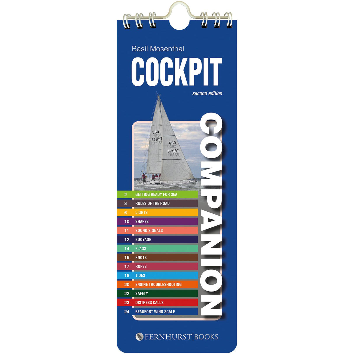 The second edition of "Cockpit Companion" by Basil Mosenthal, published by Fernhurst Books, is an essential practical seamanship guide with a blue cover depicting a sailing boat and a colorful index on topics like lights, buoys, and navigation rules.