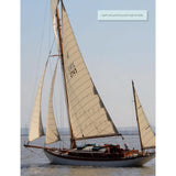 A gaff cutter yawl by Adlard Coles called Stress-Free Sailing glides on calm waters with cream sails and a wooden deck. A person is visible at the helm, mastering the steady course under a light blue sky.